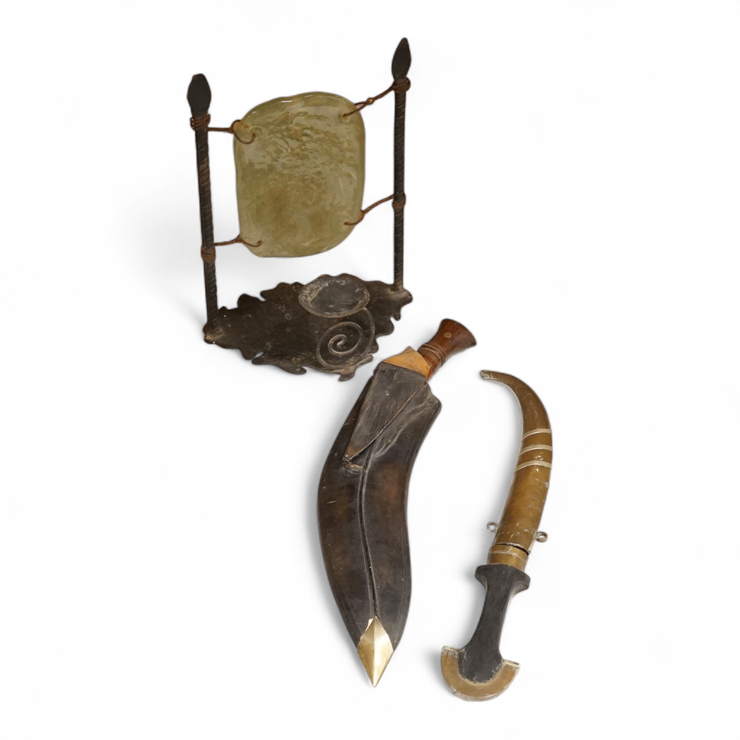 An Indian Kukri with brass mounted wooden handle its leather sheath, and a Moroccan Jambiya, together with a hardstone and wrought iron candle stand